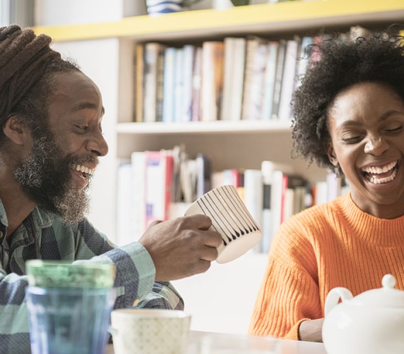 Photo of 2 older adults enjoying a conversation around a table drinking tea